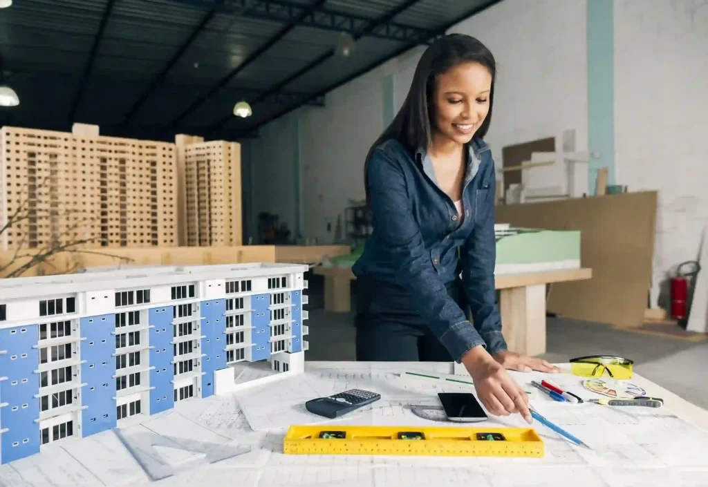 cheerful african american lady standing near model building table scaled1 Seguridad para Constructoras e inmobiliarias